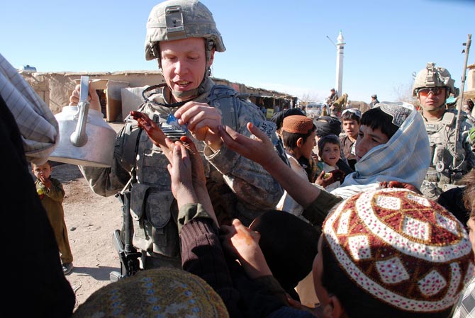 Un militar estadounidense reparte caramelos a nios afganos en la provincia de Zabul.| M. Bernab