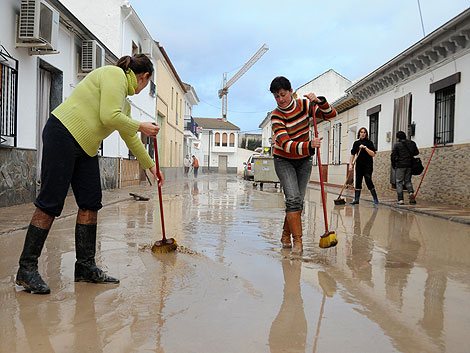 Vecinas de Valderrubio intentan eliminar el lodo acumulado en la calle. | Jess G. Hinchado