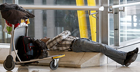Un pasajero duerme tirado en el suelo del aeropuerto de Barajas. | Efe