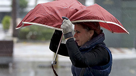 Una mujer se cubre con un paraguas en Sevilla. | Efe