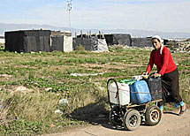 Una mujer acarrea garafas en un poblado.