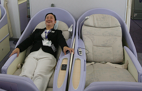 Una mujer prueba un asiento en 'primera' en un nuevo airbus A380, en Shangai.| AFP