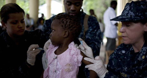 Dos enfermeras de la marina estadounidense vacunan a una niña haitiana. | Efe
