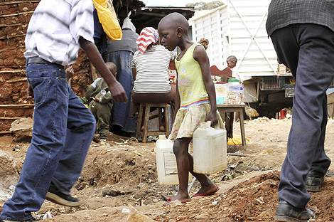 Una nia keniata carga con dos bidones de agua en Nairobi. | Reuters