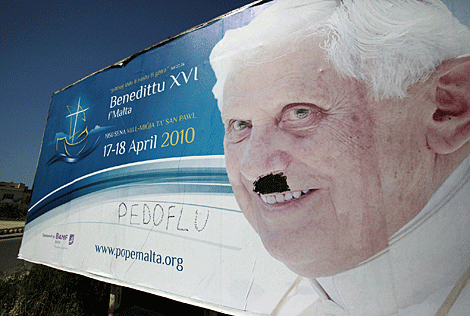 Un cartel con una foto de Benedicto XVI con pintadas en Malta. | AFP