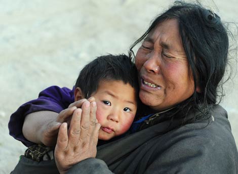 Una mujer que perdió a 10 miembros de su familia reza con su sobrino en brazos. | Afp