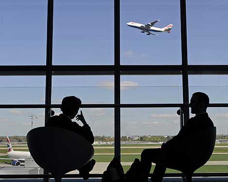 Dos pasajeros observan el despegue de un avin en la T5 de Heathrow. | Reuters