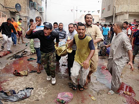 Unos hombres trasladan a un herido por las explosiones de este viernes en Bagdad. | AP
