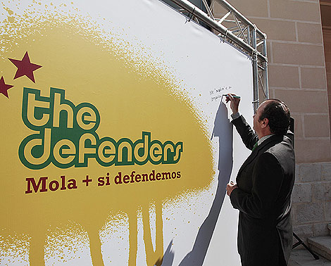 El presidente Ripoll firma sobre un panel del grupo 'The Defenders'. | E.M.