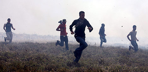 Palestinos huyen de una nube de gas lacrimgeno arrojado por soldados israeles. | Efe