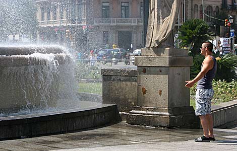 Un turista se refresca en una fuente en Barcelona. | Christian Maury