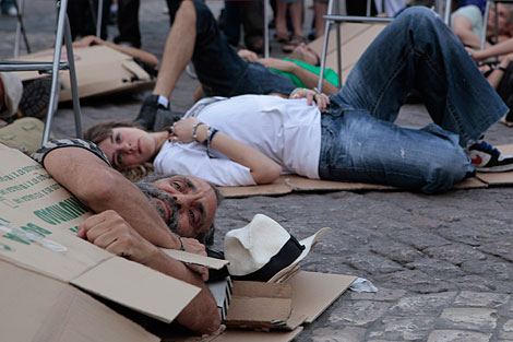 Varias personas simulan dormir entre cartones en la plaza Mayor. | Antonio Heredia