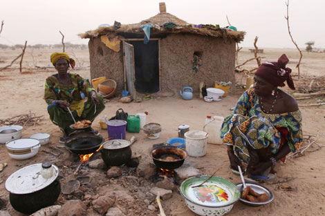 Dos mujeres nigerianas cocinan con los medios que tienen. | Ap
