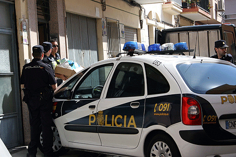 Un agente de Polica saca algunos enseres de la vivienda de la vctima. | Mguel Cabrera