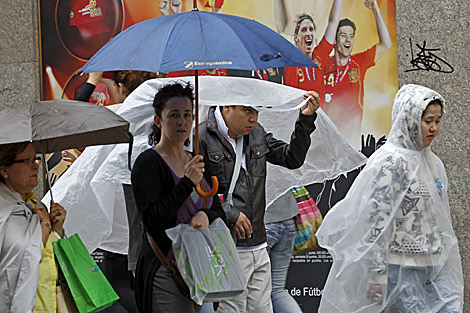 Viandantes se cubren de la lluvia el mircoles en Madrid | Efe