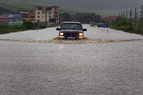 Un vehculo transita por una carretera inundada en Transilvania central, Rumania. | AFP
