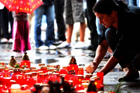 Una mujer deposita una vela en honor a las víctimas. |Afp