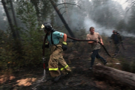 Varios bomberos tratan de sofocar uno de los incendios. | EFE