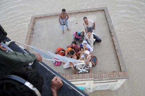 Una familia paquistan espera a ser rescatada en el tejado de su casa. | Reuters