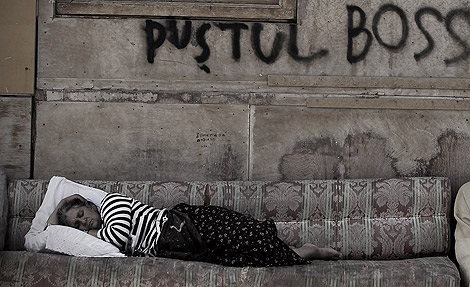 Una mujer duerme en un sofá fuera de su chabola. | Alberto di Lolli