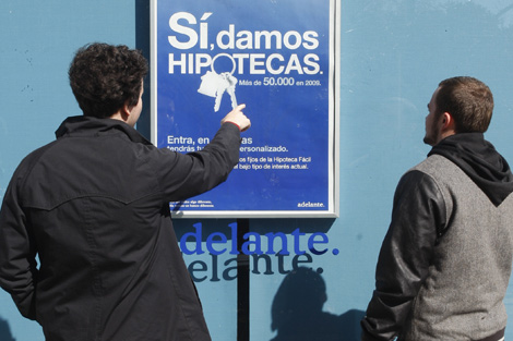 Dos jvenes observan un cartel publicitario sobre hipotecas. | Sergio Gonzlez