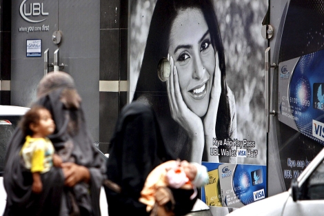 Una mujer ataviada con un burka pasa ante una sucursal bancaria. | Efe