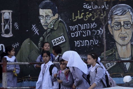 Estudiantes palestinas pasan ante un muro pintado por Hamas, en la Franja de Gaza. | Efe