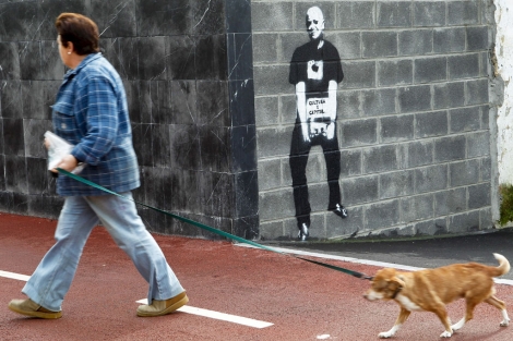 Una mujer pasea a su perro junto a la pintada de Odón Elorza. | Efe