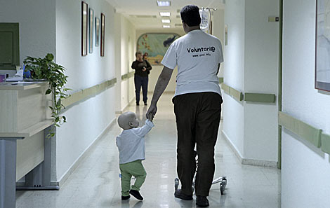 Un voluntario cuida de un niño enfermo en un hospital de Málaga. | Antonio Heredia