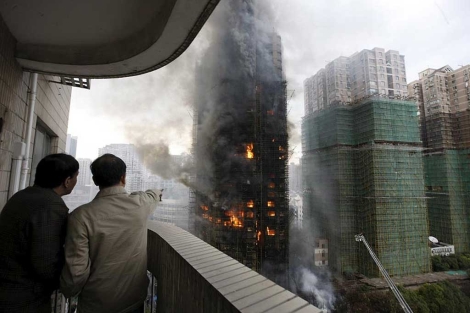 Dos chinos observan las llamas del incendio.| Efe