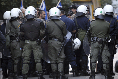 Policas antidisturbios vigilan a un grupo de ultraderechistas en una plaza de Atenas. | Efe