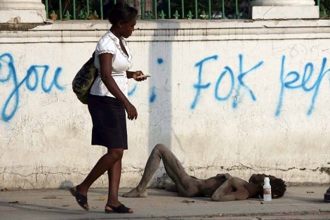 Una mujer pasa sin detenerse ante un moribundo en Puerto Prncipe. | AFP