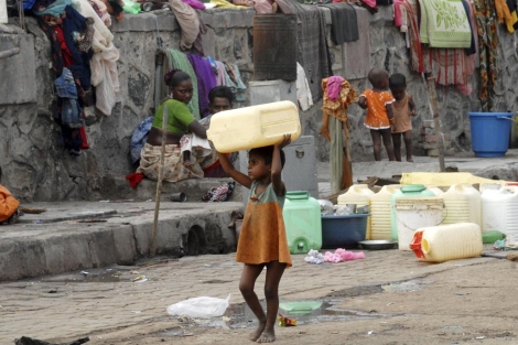 Una nia hurfana carga con un bidn de agua en India. | D. Solanki