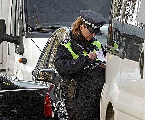 Una agente muLta a un vehculo en Madrid. (EM)