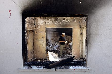 Un hombre inspecciona los restos de una casa quemada en la localidad israel Ein Hod, a las afueras de Haifa. | Efe