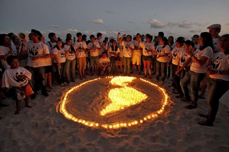 Miembros de WWF representan la tierra en las playas de Cancún. | Afp