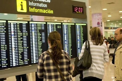 Varias personas observan los paneles de informacin de vuelos en El Prat. | Foto: Efe