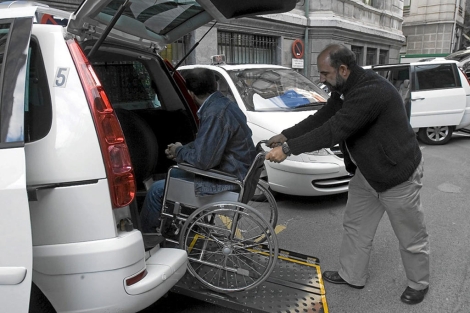 Un taxista ayuda a una persona en silla de ruedas. | Miguel Calvo