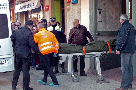 Operarios de los servicios sociales trasladan el cuerpo de la mujer asesinada. | Foto: Efe