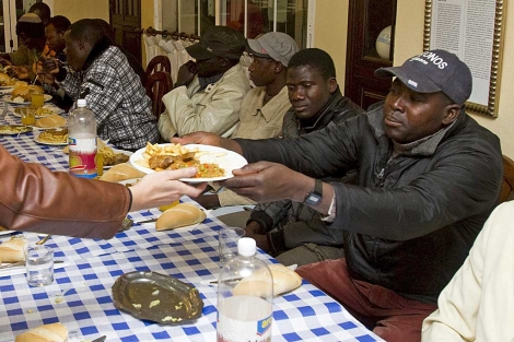 Un centenar de inmigrantes sentados a la mesa para la ocasin de despedir el ao. | Efe