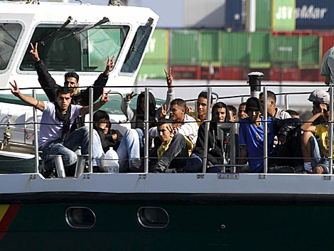 Algunos inmigrantes hacen gestos de victoria al llegar a puerto. | Efe