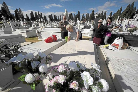Familiares y deudos limpiando una sepultura en tierra en el camposanto de Sevilla el pasado noviembre. | Jess Morn