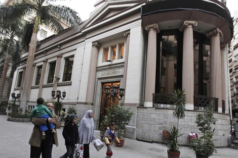 Una familia pasa cerca de una sede bancaria en el Cairo. | AP