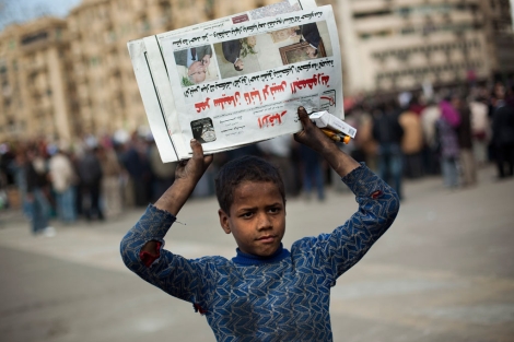 Un niño vende periódicos en la plaza Tahrir ante los manifestantes. | AP