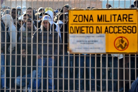 Inmigrantes esperan en las dependencias militares tras llegar a Lampedusa.| Efe
