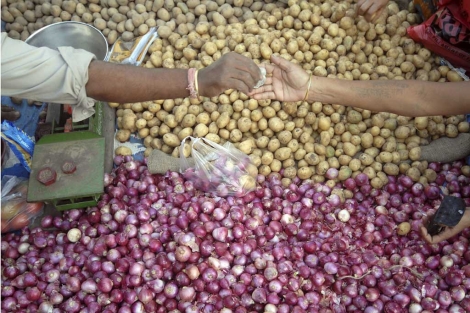 Un hombre vende cebollas y patatas en la India. | Efe