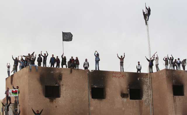 Detractores del régimen de Gadafi, en lo alto del Ayuntamiento, tras tomar Tobruk. | Reuters