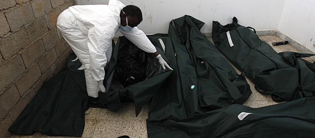 Un hombre examina varios cuerpos de personas fallecidas en las protestas de Bengasi. | AP
