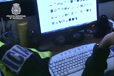 Un polica observa algunos de los archivos de contenido pedfilo intervenidos. | Polica