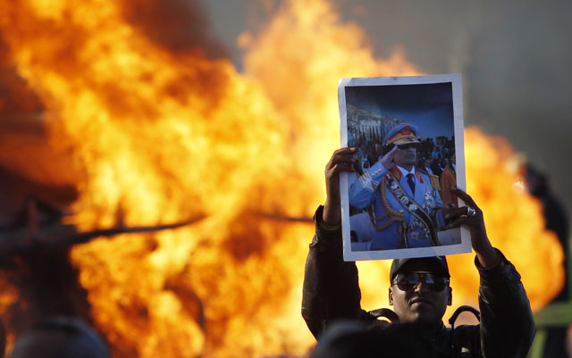 Partidarios de Gadafi corean su nombre junto al camión incendiado en Trípoli. | Reuters